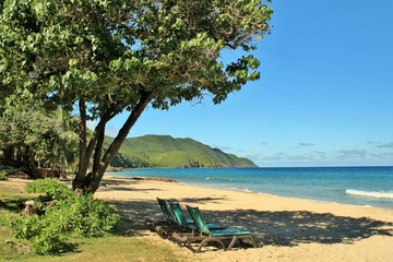 Beach chairs facing  the ocean with mountains in the background