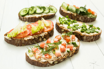 Different kinds of colorful sandwiches on white wooden background