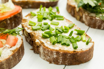 Dietary sandwich with green onions on a white table.