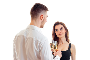 a young guy in a shirt looks at his girl and keeps wine glasses with her isolated on a white background