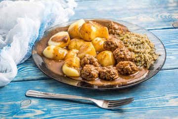 Homemade fried meatballs served with potatoes and cabbage.