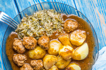Homemade fried meatballs served with potatoes and cabbage.