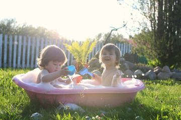 twins boy and girl in bath water outdoor
