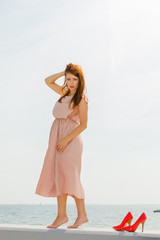 Fototapeta na wymiar Woman wearing long light pink dress on jetty