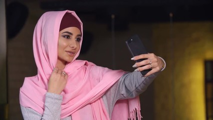 Young beautiful woman in hijab doing selfie on mobile phone camera. Muslim woman and modern technology