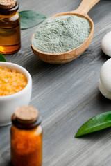 Close-up spa cosmetic products - clay, oil and sea salt on a wooden background.
