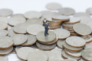 Miniature people: Business man standing on coin stack using as business and finacial concept
