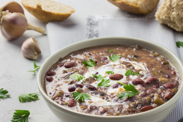  Healthy bean soup in a bowl on concrete background with whole grain bread.