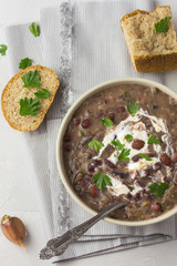 Vegan bean soup with sour cream and parsley in a white bowl.  