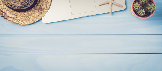 Laptop, cactus and straw hat on blue wooden table