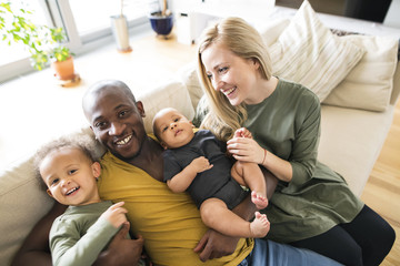 Young interracial family with little children at home.