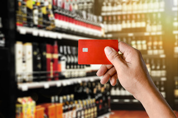a hand holding credit card on Wine Supermarket store background