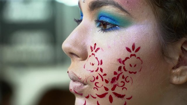 Makeup artist painting lips for a woman with face art closeup