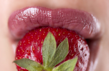 Woman lips with red strawberry on blur background. Pink lipstick. Fresh berry. Girl eating...