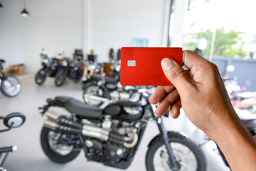 a hand holding credit card on motorcycle showroom