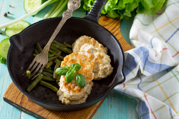 Meat cutlet from minced meat, served in a cast-iron frying pan with green beans kitchen table in a rustic style. Copy space.