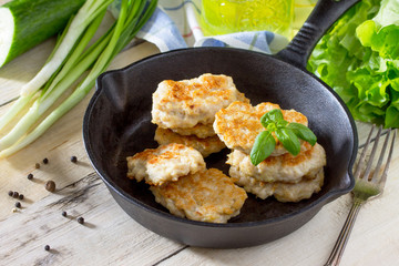 Meat cutlet from chopped mince in a cast-iron frying pan on a wooden kitchen table.