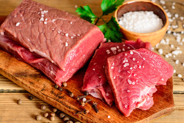 Raw beef meat on rustic wooden cutting board.