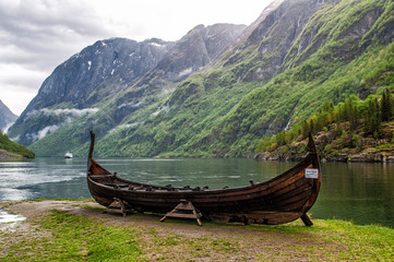 Wooden viking ship in Norway. It stands on the shores of a fjord under high mountains.