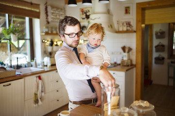 Young father at home with his little son eating biscuit together.