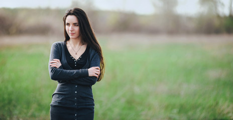A pretty brunette stands with her arms crossed. Loneliness, resentment.