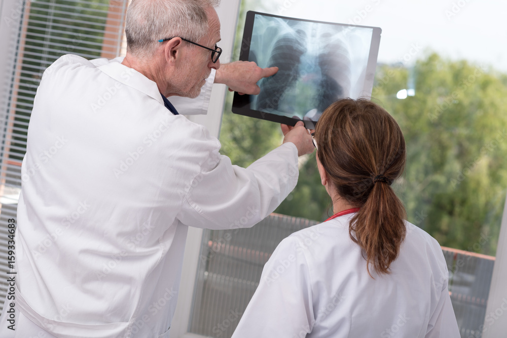 Wall mural Two doctors examining x-ray report