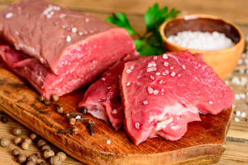 Raw beef meat on rustic wooden cutting board.