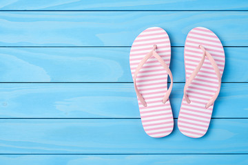 Pink flip flops on blue wooden background