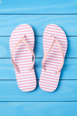 Pink flip flops on blue wooden background