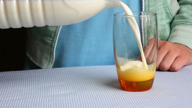 Woman pouring milk into orange glass and drinking