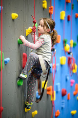 little girl climbing a rock wall indoor