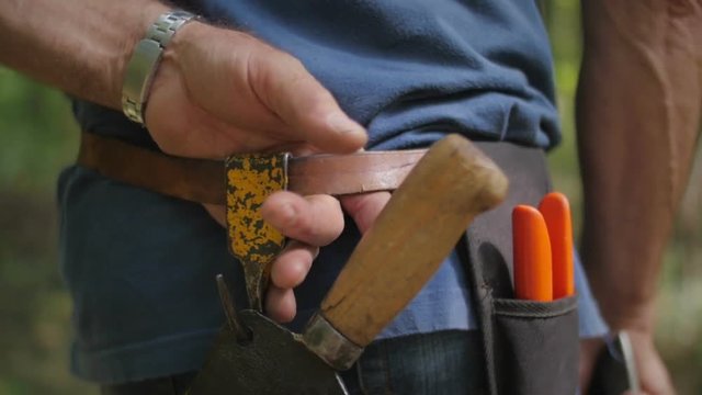 Old man's hands holding tool belt