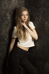 Pretty young lady with long blonde hair posing in dark room