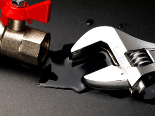 water leaking from disconnected valve and adjustable wrench, closeup