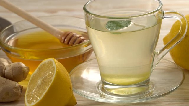 Ginger tea with lemon, mint and honey on wooden background.