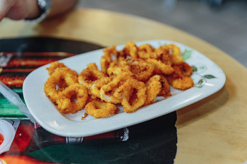 Fried squid rings in white plate in food center of the market near China Town in Kuala Lumpur, Malaysia.