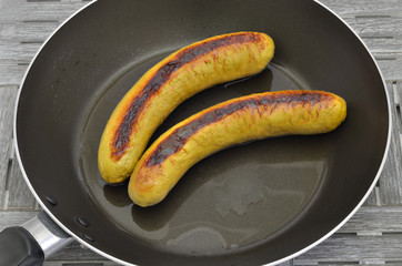Grilled Sausages in a Frying pan / two grilled sausages in a frying pan, close up, macro, full frame