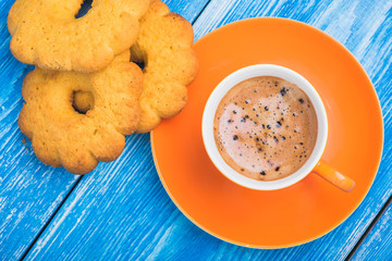 orange cup of coffee witt tasty cookie