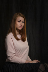 Naklejka premium Portrait of a girl at the age of nineteen on a dark background for advertising