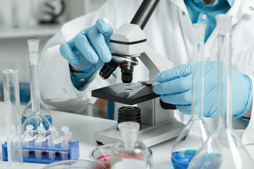 men in a laboratory microscope with microscope slide in hand