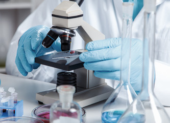 men in a laboratory microscope with microscope slide in hand