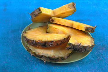 Ripe pineapple on a plate on a blue cement background