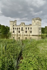 Fototapeta na wymiar Le château-fort de Bouchout baignant dans l'étang principal au milieu de la nature luxuriante du Jardin Botanique National de Belgique à Meise