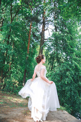 Beautiful bride in vintage white dress walking in the park.
