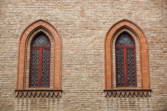Castle window in a medieval style. Double arched window on a facade of medieval wall. Biforium - ancient window with column, old architecture element of Roman and Gothic styles.