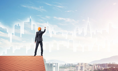 Man architect draw silhouette of modern city on blue sky. Mixed 
