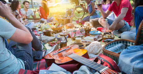 group of friends day out doing picnic. guitar on the side on focus. sun burst effect