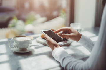 Young woman in a cafe reading a text message from her mobile phone, Bisness woman using smart phone during lunch time