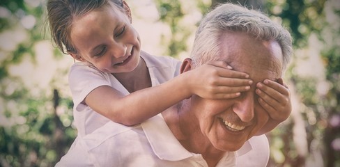 Playful girl covering grandfather eyes