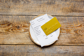 plate and receipt bill for payment by credit card wooden table background top view